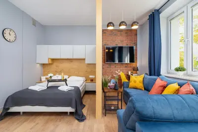 a living room with a blue couch and a bed at Kraków Trendy Studio Apartments by Noclegi Renters in Kraków