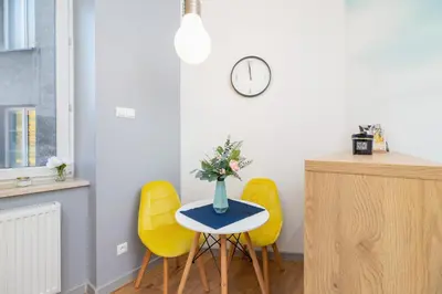 a table with yellow chairs and a vase with flowers on it at Kraków Trendy Studio Apartments by Noclegi Renters in Kraków