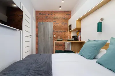 a bedroom with a white bed and a brick wall at Kraków Trendy Studio Apartments by Noclegi Renters in Kraków