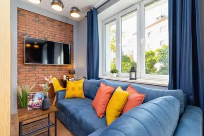 a blue couch with colorful pillows in a living room at Kraków Trendy Studio Apartments by Noclegi Renters in Kraków