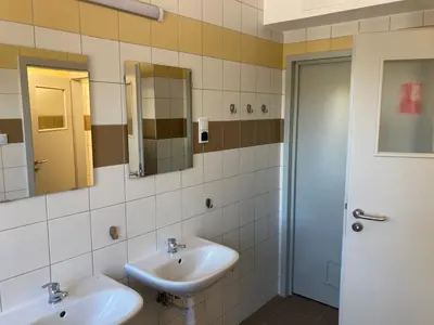 a bathroom with two sinks and two mirrors at Hostel przy Stadionie in Jaworzno
