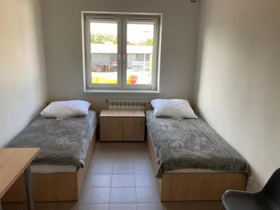 two beds in a room with a window at Hostel przy Stadionie in Jaworzno