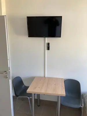 a table with two chairs and a flat screen tv on a wall at Hostel przy Stadionie in Jaworzno