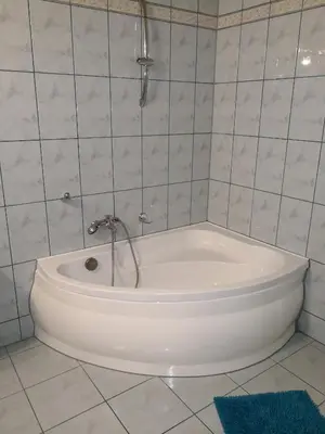 a white bath tub with a shower in a bathroom at Noclegi Hexe in Żegocina