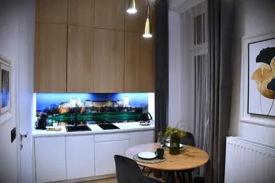 a kitchen with a table and a tv on the wall at M-Keys Apartments Kraków Old Town Kazimierz in Kraków