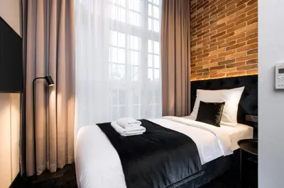 a bedroom with a bed with a brick wall at Hotel Krupnicza 30 in Kraków