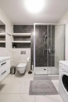 a white bathroom with a shower and a toilet at Sołtysowska Apartment in Kraków