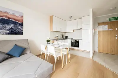 a kitchen and a living room with a couch and a table at Sołtysowska Apartment in Kraków