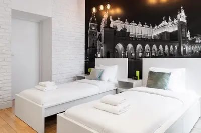 two white beds in a room with a building on the wall at Househost Apartment: Bonerowska 5/19 in Kraków