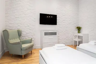 a white room with a chair and a tv on a wall at Househost Apartment: Bonerowska 5/19 in Kraków