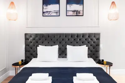 a bedroom with a bed with a black headboard and two tables at Househost Apartment: Bonerowska 5/15 in Kraków
