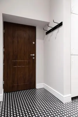 a wooden door in a room with a black and white tiled floor at Househost Apartment: Bonerowska 5/15 in Kraków