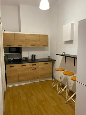a kitchen with wooden cabinets and two stools at Best View Old Town Rooms in Kraków