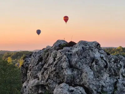 two hot air balloons flying over a rock formation at Całorocznik Skała & Apartamenty in Ryczów