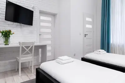 a bedroom with two beds and a desk and a tv at Househost Apartment: Bonerowska 5/11 in Kraków