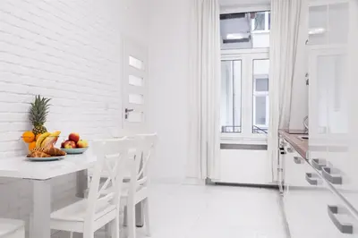 a white kitchen with a table with a bowl of fruit at Househost Apartment: Bonerowska 5/11 in Kraków