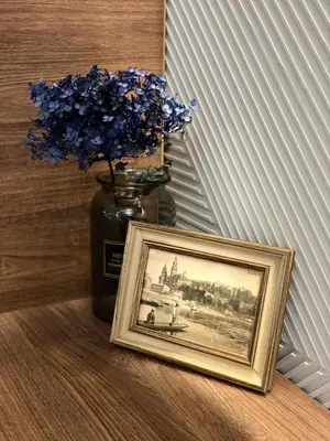 a picture and a vase with blue flowers in it at Blue Residence Orawska 5 in Kraków