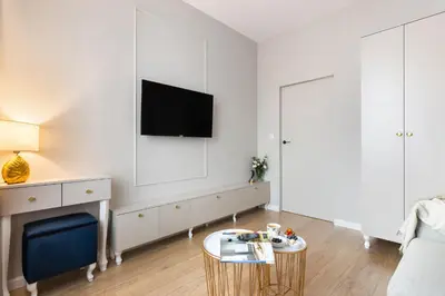 a living room with a tv on a white wall at Blue Residence Orawska 5 in Kraków