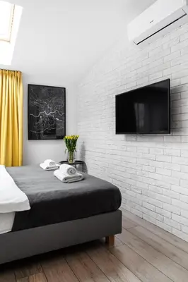 a bedroom with a bed and a tv on a brick wall at HOUSEHOST Apartament: ul. Miodowa 42/42a in Kraków