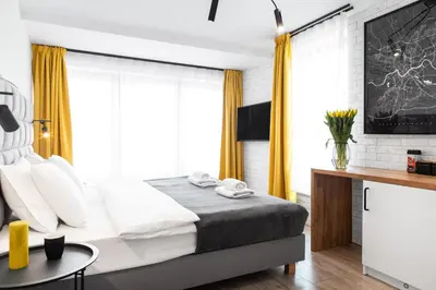 a bedroom with a large bed with yellow curtains at HOUSEHOST Apartament: ul. Miodowa 42/42b in Kraków