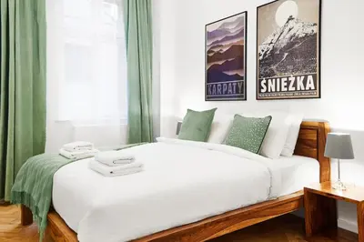 a bedroom with a large white bed with green curtains at HOUSEHOST Apartment :Starowiślna 66/9 Street in Kraków