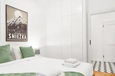 a white bedroom with a bed and a poster on the wall at HOUSEHOST Apartment :Starowiślna 66/9 Street in Kraków