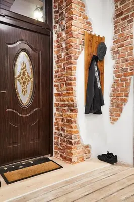 a wooden door with a coat hanging on a brick wall at HOUSEHOST Apartment: Józefa Dietla 73/7 in Kraków