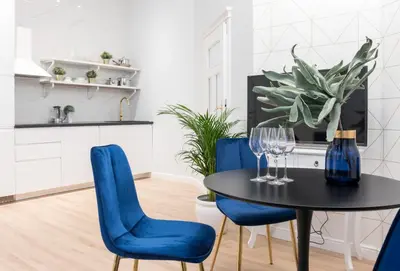 a dining room with a black table and blue chairs at HOUSEHOST Apartment: Starowiślna Street 36/27 in Kraków