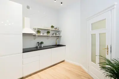 a kitchen with white cabinets and black countertops at HOUSEHOST Apartment: Starowiślna Street 36/27 in Kraków