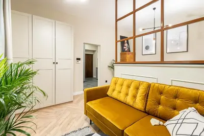a living room with a yellow couch and a window at HOUSEHOST Apartment : Topolowa 26/17 in Kraków