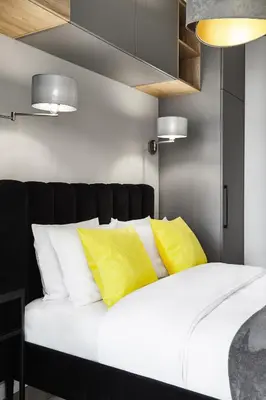 a bedroom with a white bed with yellow pillows at HOUSEHOST Apartment :Miodowa 42/4a in Kraków