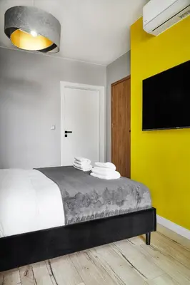 a bedroom with a bed and a yellow wall at HOUSEHOST Apartment :Miodowa 42/4a in Kraków