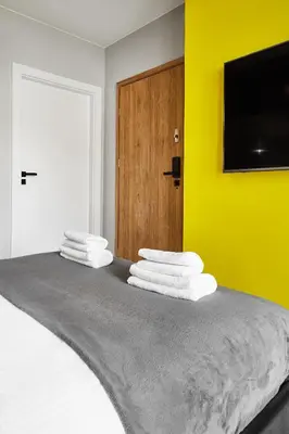 a bedroom with a bed with a yellow wall at HOUSEHOST Apartment :Miodowa 42/4a in Kraków