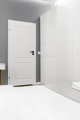 a bedroom with a white bed and a white door at HOUSEHOST Apartment: Św.Gertrudy 10/2.11 in Kraków