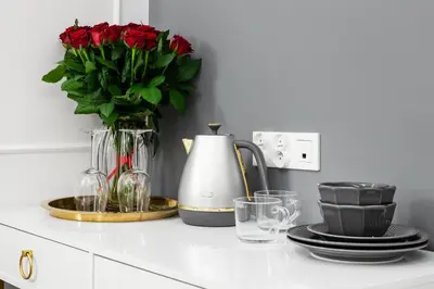 a counter with a vase of red roses and glasses at HOUSEHOST Apartment: Św.Gertrudy 10/2.11 in Kraków
