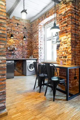 a dining room with a table and chairs and a brick wall at HOUSEHOST ApartmenI: Podbrzezie 2/20 in Kraków