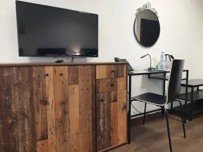 a living room with a tv and a desk with a chair at Hotel Świt in Kraków
