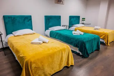 three beds in a room with yellow sheets at Hotel Świt in Kraków