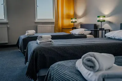 a room with three beds with towels on them at Hotel Świt in Kraków