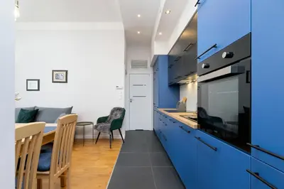 a kitchen with blue cabinets and a table with chairs at Sweet Family Apartment Chodkiewicza Rondo Grzegórzeckie by Noclegi Renters in Kraków