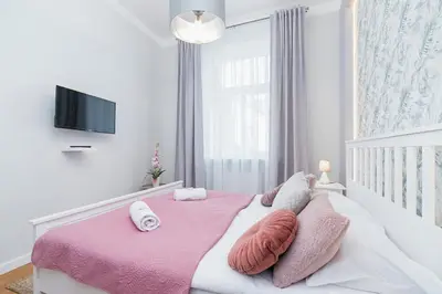 a bedroom with a large bed with pink sheets and pillows at Sweet Family Apartment Chodkiewicza Rondo Grzegórzeckie by Noclegi Renters in Kraków