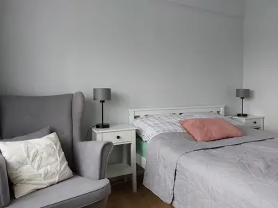 a bedroom with a bed and a chair next to a bed sidx sidx at Dom przy lesie in Zawadka