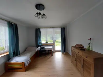 a bedroom with a bed and a desk and a table at Dom przy lesie in Zawadka