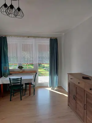 a living room with a table and a window at Dom przy lesie in Zawadka