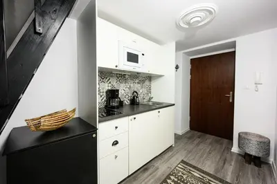 a kitchen with white cabinets and a black counter at Native Apartments Studencka 25 in Kraków