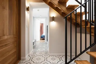 a hallway with a staircase and a floor with tiles at City of the Kings-Old Town Pastel Apartment in Kraków