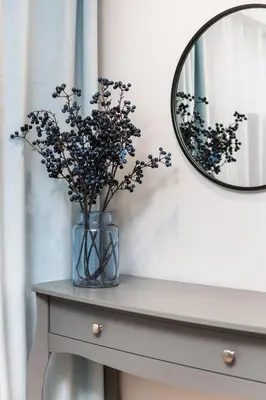a vase with flowers on a table next to a mirror at City of the Kings-Old Town Pastel Apartment in Kraków