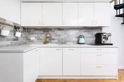 a white kitchen with white cabinets and a sink at City of the Kings-Old Town Pastel Apartment in Kraków
