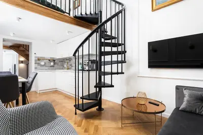 a black spiral staircase in a living room with a table at City of the Kings-Old Town Pastel Apartment in Kraków