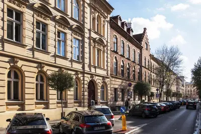 a row of cars parked on a street next to a building at City of the Kings-Old Town Pastel Apartment in Kraków